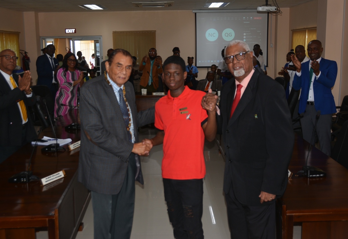 Chairman of the St. Elizabeth Municipal Corporation and Mayor of Black River, Councillor Derrick Sangster (left), and Minority Leader and Councillor of the Braize River Division, Donovan Pagon (right), shake hands with grade 11 B.B. Coke High School student, Daejuan Gordon, at the Corporation’s monthly meeting on Thursday, October 12. During the meeting, Daejuan received a standing ovation and words of commendation on behalf of his peers Garry Bartley, Dejuan Powell, Leon Barnes, and Khari Green, for acting swiftly in getting injured schoolmate, Jaheim Powell, to a medical facility on September 28.