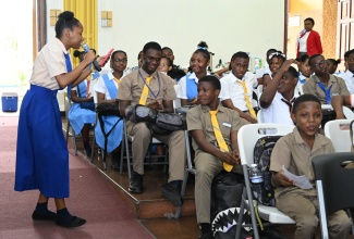 Students attending the National Child Month Committee’s recent youth forum at the Caenwood Centre in Kingston are entertained by one of their peers from Holy Childhood High School.

