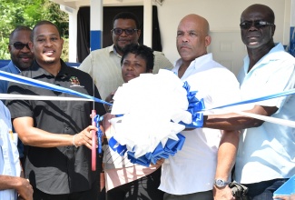 Minister of Agriculture, Fisheries and Mining, Hon. Floyd Green (second left) and Member of Parliament for St. Thomas Western, James Robertson (left), unveil a sign for a communal milking parlour that was handed over in Hillside, St. Thomas, on November 7. Also pictured are (from third left) Chairman of the Jamaica Dairy Development Board, Dr. Derrick Deslandes; Councillor Caretaker for the Seaforth Division, Sheroo Stevens; Chairman of the St. Thomas Rural Agricultural Development Authority (RADA), Dean Jones; and Chief Technical Director in the Ministry of Agriculture, Fisheries and Mining, Orville Palmer.