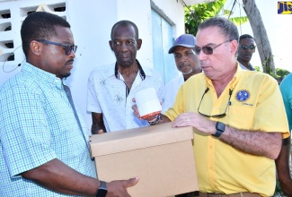 Minister of Science, Energy, Telecommunications and Transport Hon Daryl Vaz (right), displays a solar-powered lamp to Member of Parliament for St James Central and Deputy Speaker of the House of Representatives, Heroy Clarke, during a tour of communities in St James that are to benefit under the Rural Electrification Programme (REP), on November 10. Sharing the moment (from second left) are Minister of State in the Ministry of Science, Energy, Telecommunications and Transport, Hon. J.C. Hutchinson, and Managing Director, Jamaica Social Investment Fund (JSIF), Omar Sweeney.

