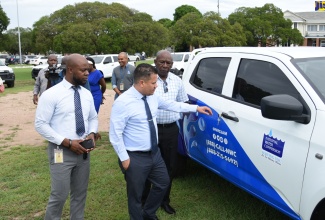 Minister without Portfolio in the Ministry of Economic Growth and Job Creation, Senator the Hon. Matthew Samuda (centre); Acting Vice President of Operations, National Water Commission (NWC), Herman Fagan (left); and NWC Technical Services Manager, Aubrey Williams, view one of the 30 pickup trucks that were added to the entity’s fleet today (November 8). They were handed over at the NWC’s Marescaux Road office in Kingston by the Minister.

