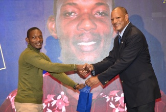 Senior General Manager, GraceKennedy, Carl Barnett (right), makes a presentation to Carlington Darby for over 15 years of meritorious service to the National Irrigation Commission (NIC) Limited, during the agency’s 36th anniversary luncheon and long service awards ceremony on November 28 at the Jamaica Pegasus Hotel in New Kingston.

