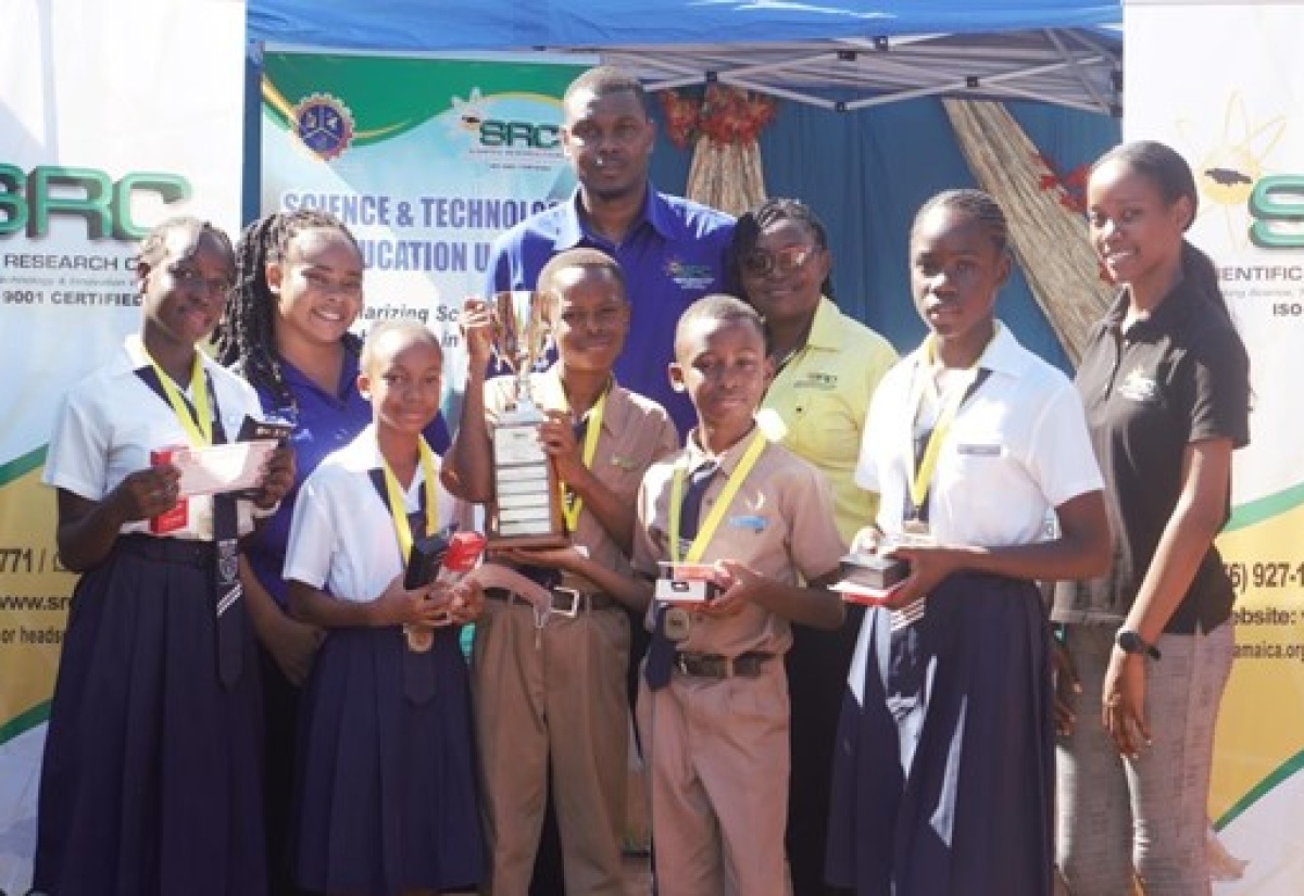 The Grove Town Primary and Infant School team raise the winning trophy in the Scientific Research Council’s  (SRC) inaugural  Science, Technology, Engineering and Mathematics STEM Olympiad. Members of the SRC visited the institution in Manchester recently to make the presentation.