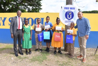 Member of Parliament for St. Catherine West Central, Dr. the Hon. Christopher Tufton (right), and Chief Executive Officer of the Universal Service Fund (USF), Dr. Daniel Dawes (left), with students who received tablet computers from the agency, during the commissioning of the Brown’s Hall free Wi-Fi system service on November 8.