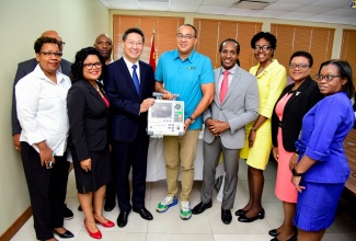 Minister of Health and Wellness, Dr. the Hon. Christopher Tufton (fifth right); Ambassador of the People's Republic of China to Jamaica, His Excellency Chen Daojiang (sixth right); Minister of State in the Ministry of Foreign Affairs and Foreign Trade, Hon. Alando Terrelonge (fourth right), and other stakeholders share a photo opportunity, following the donation of medical equipment and supplies by the People's Republic of China, at the Ministry of Health and Wellness offices in New Kington, on December  6.