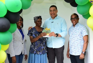 Prime Minister the Most. Hon. Andrew Holness (second right), gives the keys to beneficiary of a one-bedroom unit under the New Social Housing Programme (NSHP) in Belfield, St. Mary, Susettee Hudson, at the official handover of the house on December 21. Looking on (from left) are Permanent Secretary in the Ministry of Economic Growth and Job Creation, Arlene Williams and Member of Parliament for St. Mary, South Eastern, Dr. the Hon. Norman Dunn.
