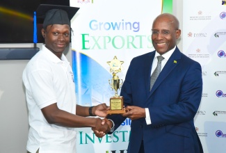 Minister of Industry, Investment and Commerce, Senator the Hon. Aubyn Hill (right), presents a trophy to the top student, Recardo McLarty from Sagility business process outsourcing company. Occasion was the graduation ceremony for supervisors in the global services sector held on December 6 at the Jamaica Promotions Corporation (JAMPRO) in Kingston.

