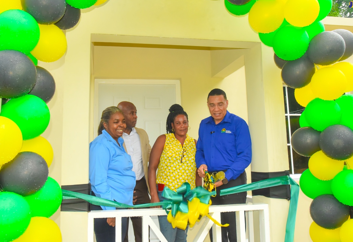 Prime Minister, the Most Hon. Andrew Holness (right), cuts the ribbon to mark the handover of a two-bedroom house, built under the New Social Housing Programme (NHSP), to Bridget Brown  (second right) in Morgan’s Forrest, Clarendon on Friday (December 15). Looking on (from left) are Chairperson for the Oversight Committee of the NSHP, Judith Robb Walters; and Member of Parliament for Clarendon Northern, Dwight Sibblies.

 