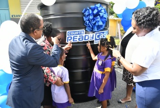 Minister of State in the Ministry of Labour and Social Security and Member of Parliament for St. Mary South Eastern, Dr. the Hon. Norman Dunn (left), joins students, teachers and representatives from Courts Ready Cash at the handover of a water tank to Clonmel Primary and Infant School. The presentation was made at the institution in Highgate, St. Mary, on December 6. Bromley Primary, also in the parish, received a water tank on the day. Courts Ready Cash is providing black water tanks to schools across the island in support of government’s initiative to ensure access to potable water in drought-affected communities.


