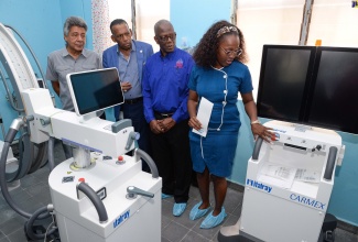 Radiographer at the Bustamante Hospital for Children (BHC), Andreanna Thompson (right), points out features of equipment handed over by the Culture, Health, Arts, Science and Education (CHASE) Fund, during a ceremony at the hospital in St. Andrew on Tuesday (December 12). Looking on (from left) are Chairman of the BHC, Kenneth Benjamin; Chief Executive Officer of the CHASE Fund, W. Billy Heaven; and Chairman of the South East Regional Health Authority (SERHA), Wentworth Charles.

