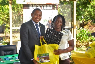 Minister of Agriculture, Fisheries and Mining, Hon. Floyd Green (left), presents a backyard gardening kit to Corporate Area resident Arlene Nelson, at the Rural Agricultural Development Authority (RADA) St. Andrew Parish Office on Monday (December 18). The Ministry, in collaboration with RADA, is continuing the ‘Backyard Garden Kit’ initiative with the aim to assist residents in urban and peri-urban areas to grow vegetables and herbs in small spaces or their backyards.


