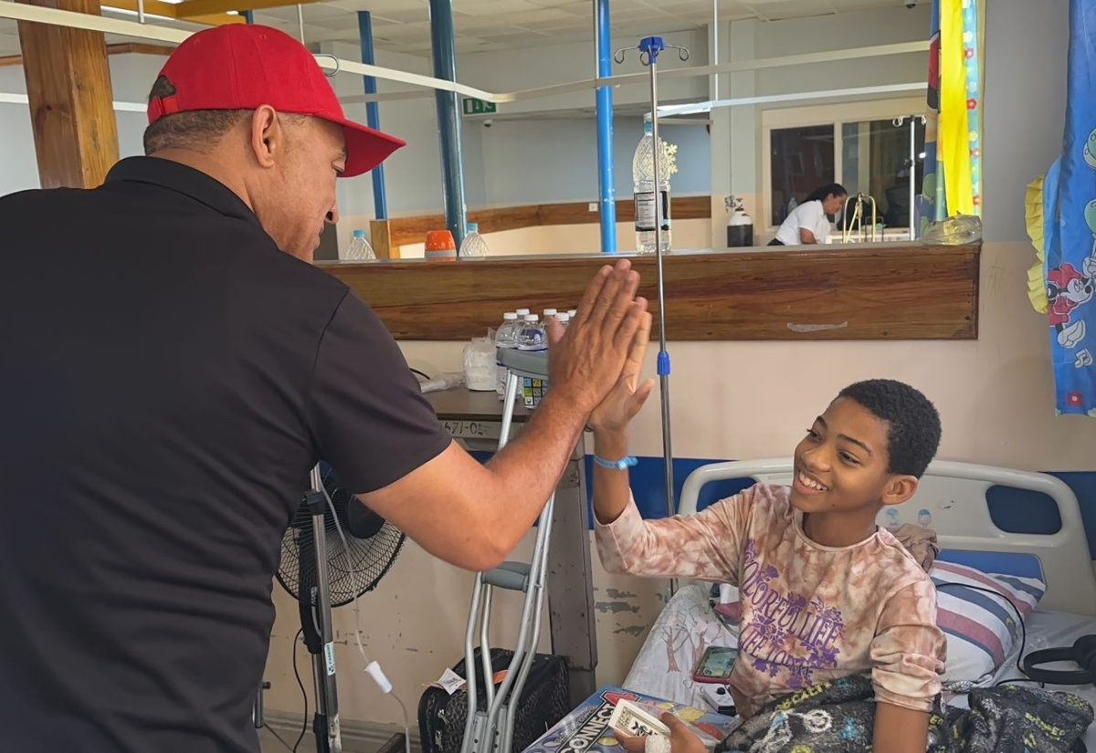 Health and Wellness Minister, Dr. the Hon. Christopher Tufton, exchanges high fives with Maliek Stephenson, who is a patient of the Mandeville Regional Hospital, during a visit to the facility in Manchester on Thursday (December 21), where he brought gifts and smiles to the young patients.
 