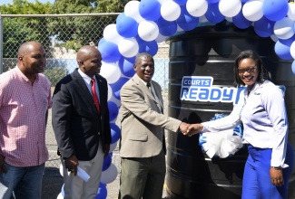 General Manager for Courts Ready Cash, Atasha Bernard (right), hands over a water tank to Principal of Gaynstead High School, Liston Aiken (second right), at the institution in Kingston on November 30. Looking on (from left) are Member of Parliament, St. Andrew South Eastern, Julian Robinson, and Senior Education Officer, Ministry of Education and Youth, Dr. Ewan Williams. The tank was provided under the company’s corporate social responsibility initiative, aimed at improving access to water in schools across the island.

