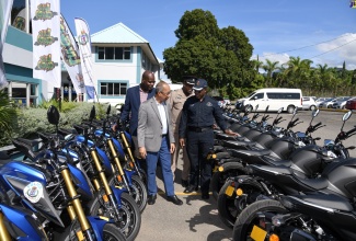 Deputy Prime Minister and Minister of National Security, Hon. Dr. Horace Chang (left), is shown several of the 74 new motorcycles for the Jamaica Constabulary Force by Deputy Commissioner of Police, Dr. Kevin Blake (right), during Friday’s (December 1) handover ceremony at the Police Commissioner’s Office in Kingston. Others (from left, background) are Deputy Commissioner of Police Fitz Bailey and Commanding Officer, Public Safety and Traffic Enforcement Branch, Assistant Commissioner of Police Gary McKenzie
