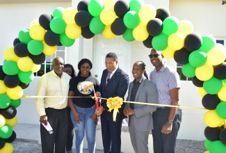 Prime Minister, the Most Hon. Andrew Holness (third right), cuts the ribbon to hand over a three-bedroom house to Shaneil Francis (third left) in Casabanna, Clifton, St. Catherine on December 19. The house is the latest unit delivered under the New Social Housing Programme (NSHP). Sharing in the moment (from left) are Member of Parliament, St. Catherine Southern, Fitz Jackson; Chief Technical Director, Ministry of Economic Growth and Job Creation, Authrine Scarlett [partially hidden]; Member of Parliament for St. Catherine East Central, Hon. Alando Terrelonge; and Member of Parliament, St. Catherine South Eastern, Robert Miller.