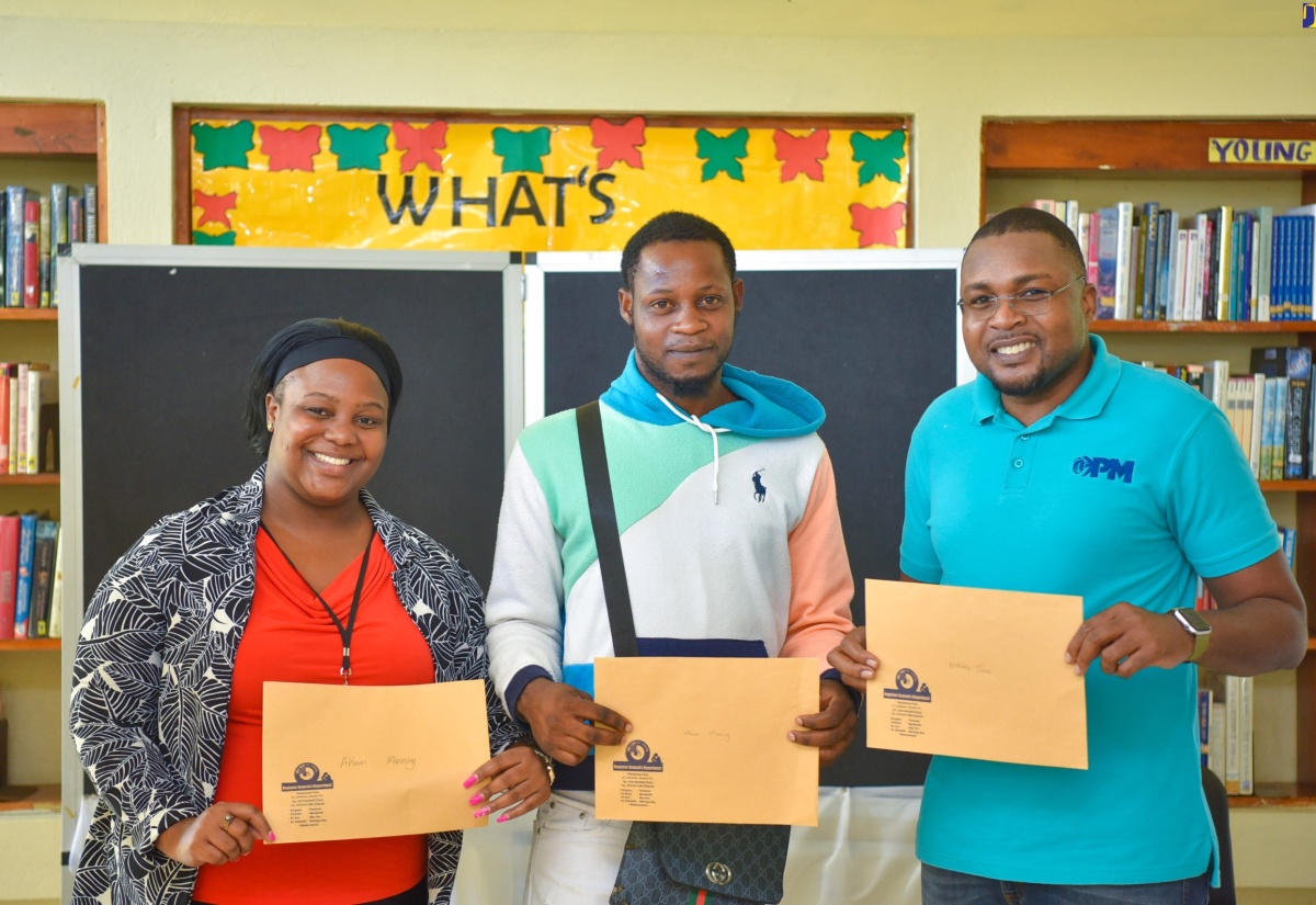 Member of Parliament for Clarendon North Central, Hon. Robert Morgan (right), and Customer Service Representative at the Registrar General’s Department (RGD), Shaniece Stewart (left), join Ackeem Manning in showing off his new birth certificate. Occasion was the presentation of birth certificates to 17 residents under ‘Operation Birthright’ during a recent ceremony at the Chapelton Library.