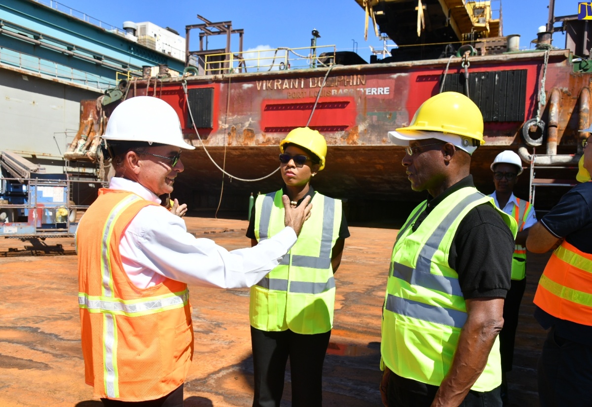 Minister of Industry Investment and Commerce, Senator the Hon. Aubyn Hill (right), and Chief Executive Officer, Jamaica Special Economic Zone Authority (JSEZA), Kelli- Dawn Hamilton (centre), listen as Chief Executive Officer, German Ship Repair Jamaica (GSRJ) Limited, Colonel Martin Rickman, explains the operations of the GSRJ's 235 metre-long Panamax-size floating dry dock, JAM-DOCK-1, which is  moored at the entity’s shipyard along the Sir Florizel Glasspole Highway stretch of Kingston Harbour. Teams from the Ministry and the JSEZA toured the shipyard on Tuesday (January 16).