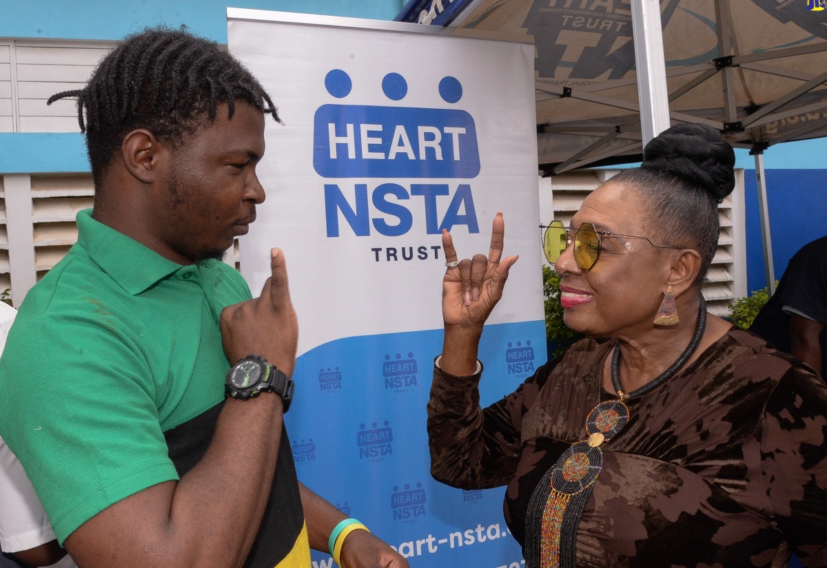 Minister of Culture, Gender, Entertainment and Sport, Hon. Olivia Grange, interacts with prospective HEART/NSTA Trust student, Michael Thomas, who is hearing-impaired, during the agency’s recruitment drive at Eltham Park Primary School in St. Catherine on January 28.

