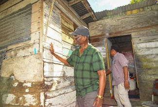Minister of Local Government and Community Development, Hon. Desmond McKenzie (in foreground), and Chief Technical Director in the Ministry, Dwight Wilson, inspect the home of Russia, Westmoreland resident, Alfonso Bruce, during a visit on Wednesday (January 17).