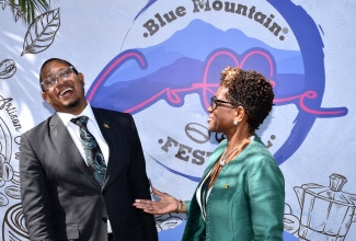 Minister of Agriculture,  Fisheries and Mining, Hon. Floyd Green (left), enjoys a good laugh with Executive Director of Devon House, Georgeia Robinson, during Tuesday’s (January 9) launch of the Blue Mountain Coffee Festival, held at Devon House in Kingston.


