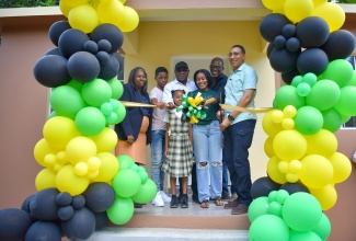 Prime Minister, the Most Hon. Andrew Holness (right), cuts the ribbon to hand over a three-bedroom unit under the New Social Housing Programme (NSHP) to Angelyn Miller (third from right) of Johns Hall, St. James, and her children on Monday, January 8. Sharing in the moment are (from left) Chairperson of the Oversight Committee of the NSHP, Judith Robb; Tourism Minister and Member of Parliament for St. James East Central,  Hon. Edmund Bartlett; and Councillor for the Springmount Division, Uvel Graham.

