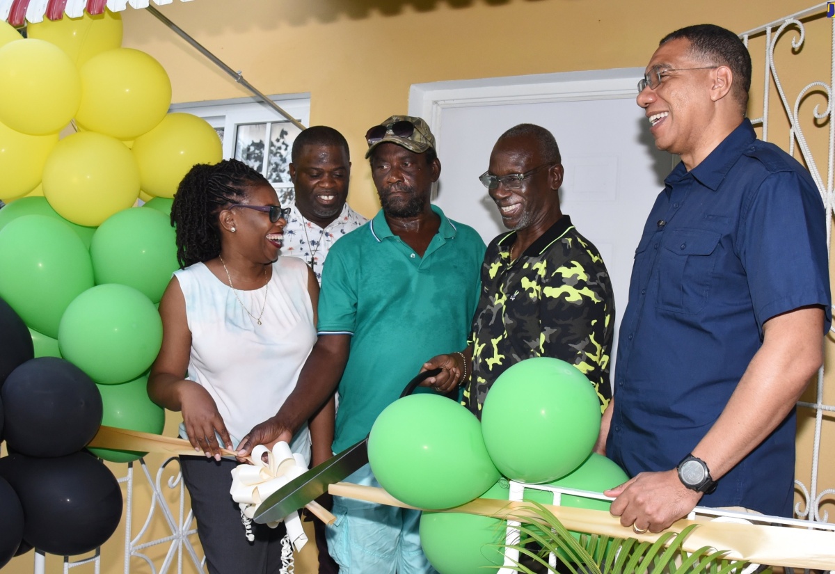 Prime Minister, the Most Hon. Andrew Holness (right), looks on as Minister of Local Government and Community Development, Hon. Desmond McKenzie (second right), cuts the ribbon to hand over a new housing unit to Carlton Kent (centre) in Chambers Pen, Hanover on Friday (January 20). Sharing the moment are Member of Parliament for Hanover Western, Tamika Davis (left); and Councillor for the Riverside Division, Daren Barnes.