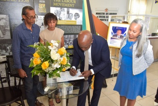 Minister of Labour and Social Security, Hon. Pearnel Charles Jr., (second right), signs the condolence book for late former Permanent Secretary, Anthony Irons, who passed away on February 1. Mr. Irons was Permanent Secretary in the Labour Ministry from 1989 to 2001. Looking on (from left) are Mr. Irons’ nephew and niece, Damion Edwards and Nicola Chung, and Permanent Secretary in the Ministry, Colette Roberts Risden. The condolence book was signed at the Ministry’s North Street office in downtown Kingston on Tuesday (February 13).