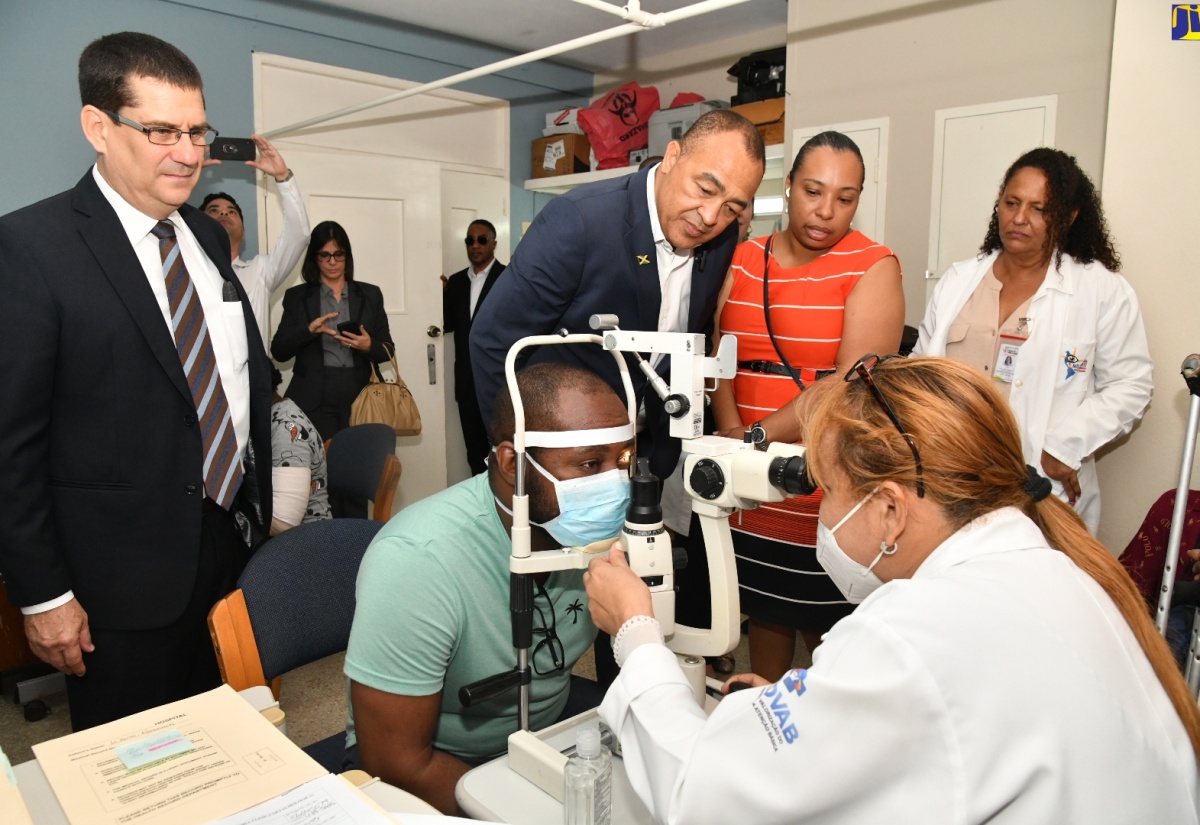 Health and Wellness Minister, Dr. the Hon. Christopher Tufton (standing, second left); and Cuba’s Ambassador to Jamaica, His Excellency Fermîn Gabriel Quiñones Sanchéz (left), observe as Cuban Ophthalmologist, Mauritza Perez Blanco, administers an eye test on patient George Scott. Occasion was a tour of the St. Joseph’s Hospital in St. Andrew on February 6, which is one of two public health facilities where the Jamaica-Cuba Eye Care Programme operates. The other is the Kingston Public Hospital. Also looking on are Coordinator for the Jamaica-Cuba Eye Care Programme, Natasha Biggs (second right); and Cuban Ophthalmologist, Mayra Chaveco Almanza.

