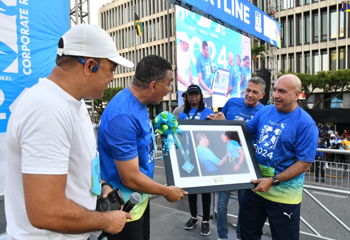 Prime Minister the Most. Hon. Andrew Holness ({second left) receives a framed photograph from President and Chief Executive Officer, Sagicor Group Jamaica, Christopher Zacca (right) at the 26th staging of the Sagicor Sigma ‘Honour’ Run in Kington on Sunday (February 18). Others (from left) are Minister of Health and Wellness, Dr. the Hon. Christopher Tufton; and Chairman, Sagicor Group Jamaica Limited, Peter K. Melhado.