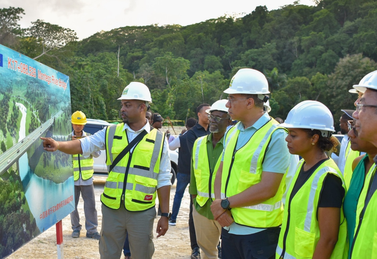 Prime Minister, the Most Hon. Andrew Holness (third left), looks on as Managing Director of the National Road Operating and Constructing Company Limited (NROCC), Stephen Edwards (left), outlines the scope of works on the Montego Bay Perimeter Road in St. James during a tour of the project on January 8. The Prime Minister was accompanied by Minister of Local Government and Community Development, Hon. Desmond McKenzie (second left); Minister of Legal and Constitutional Affairs, Hon. Marlene Malahoo Forte (third right); and Deputy Prime Minister and Minister of National Security, Hon. Dr. Horace Chang (right).   