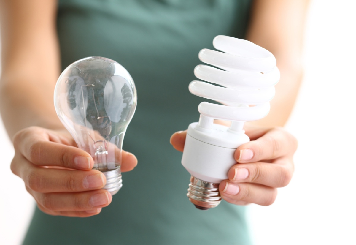 Hands holding traditional and energy efficient light bulbs. 
