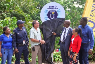 Minister of Science, Energy, Telecommunications and Transport, Hon. Daryl Vaz (third left), looks on as Chief Executive Officer, Universal Service Fund (USF), Dr. Daniel Dawes (third right), unveils a sign during the community Wi-Fi launch in Skibo, Portland, on Wednesday (January 31). Looking on are (from left) Community Development Officer, Social Development Commission, San-Tawna Nolan; Detective Inspector Horace Harris, Buff Bay Police Station; Principal, Skibo Primary School, Sanchia Williams Burrell; and Councillor/Caretaker, Hope Bay Division, Orton Manahan.

