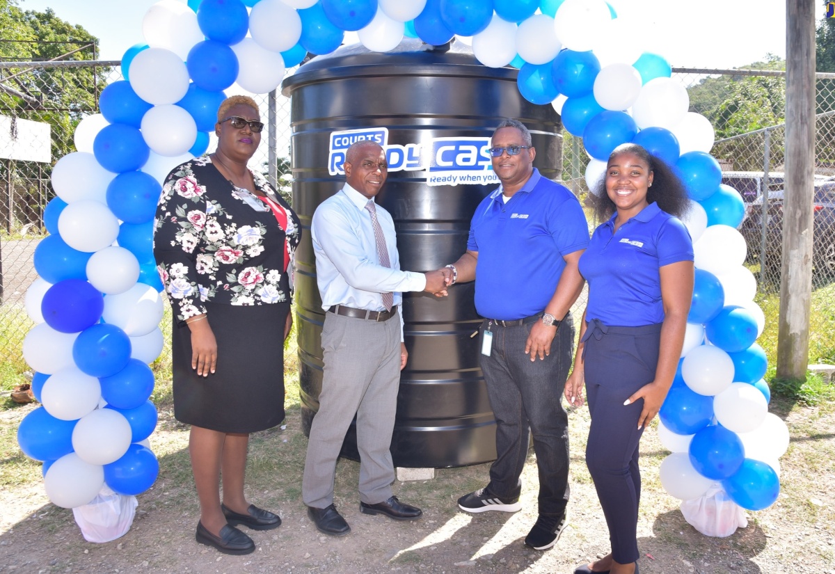 Principal of Windsor Castle All-Age School, Robert Watson (second left), shakes hands with Courts Ready Cash Marketing Officer (Events), Carlos Wright, following the presentation of a water tank (pictured in the background) to the institution. The presentation was made during the official handover ceremony at the school in Windsor Castle, Portland on Thursday (February 29). Sharing the moment are (from left) Senior Education Officer in the Ministry of Education and Youth, Tanya Sinclair; and teacher, Windsor Castle All-Age Infant Department, Ann Marie Roulston. The donation formed part of Courts Ready Cash’s islandwide water tank intitative. Under the venture, water tanks are donated to selected primary and secondary schools in the parishes of Clarendon, St. Thomas, Portland, St. Mary, St. Catherine and Hanover.

