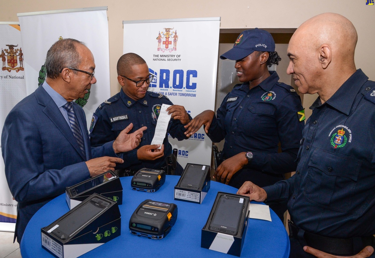 Deputy Prime Minister and National Security Minister, Hon. Dr. Horace Chang, observes as Jamaica Constabulary Force (JCF) Officer, Byron Martindale, exhibits a ticket generated by the e-ticketing system during a demonstration of the handset device by Constable Morata Murdock. Also observing is Police Commissioner, Major General Antony Anderson. The occasion was the handover of 3,000 handsets and printers to the JCF’s Public Safety Traffic Enforcement Branch (PSTEB) in Kingston in December.

