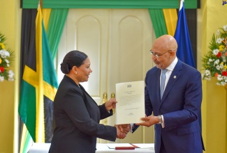Governor-General, His Excellency the Most Hon. Sir Patrick Allen (right), presents newly appointed Custos Rotulorum for the parish of Clarendon, Edith Chin, with the Instrument of Office, during the swearing-in ceremony at King’s House on March 1.