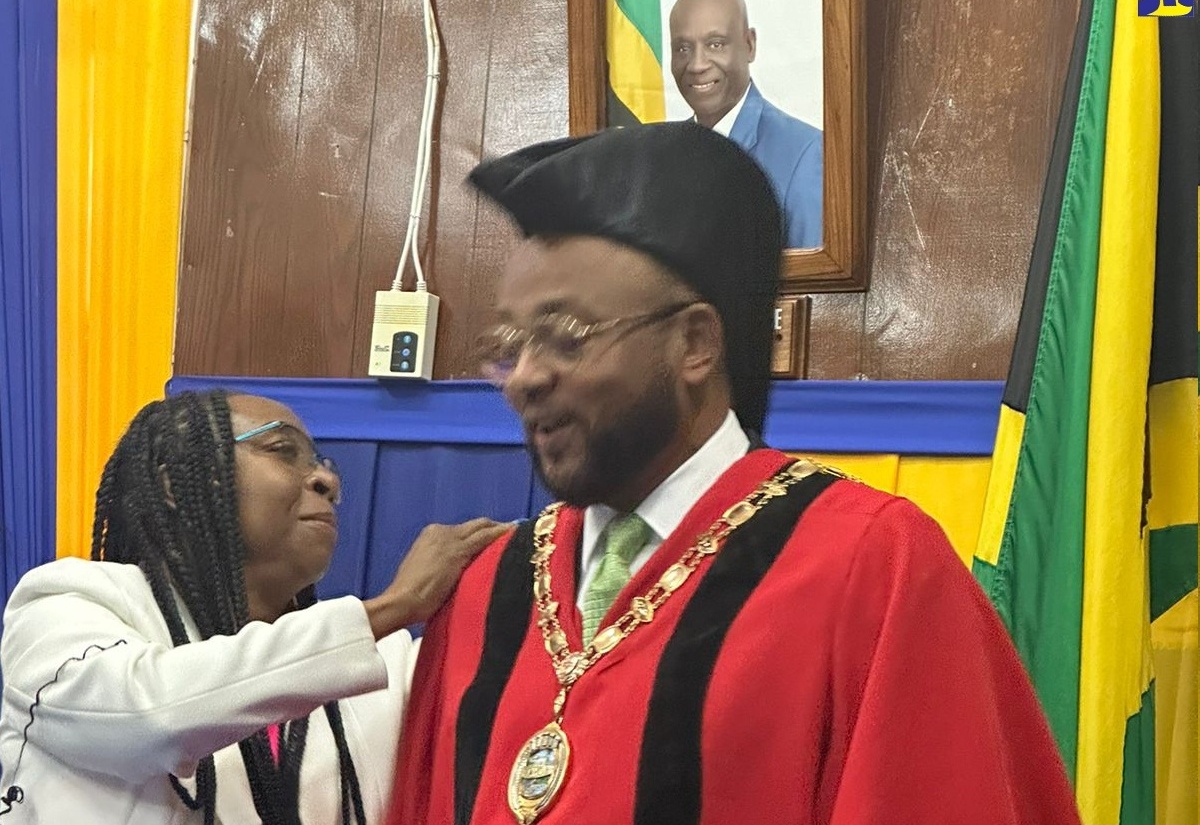 Mayor of St. Ann's Bay, Michael Belnavis (right) is helped into his mayoral garb by Chief Executive Officer of the St. Ann Municipal Corporation, Jennifer Brown-Cunningham at the swearing in ceremony held on March 7 at the Municipal Corporation.