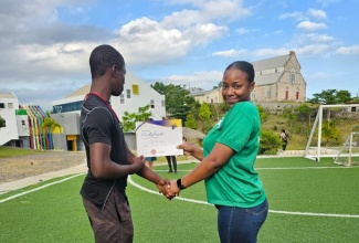 Jamaica Information Service (JIS) Digitisation Clerk, Tyesha Richards, presents a certificate of achievement to a resident of the Mount Olivet Boys’ Home in Manchester during their annual Sports Day on Saturday, April 6. The agency adopted the Home in 2009 as their main Corporate Social Responsibility Project. 

