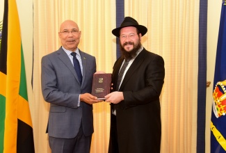 Governor General, His Excellency the Most Hon. Sir Patrick Allen (left) is handed a book by Chief Rabbi of Jamaica and Director of Chabad Jamaica, Rabbi Yaakov Raskin, during a courtesy call at King’s House on Friday (April 19).