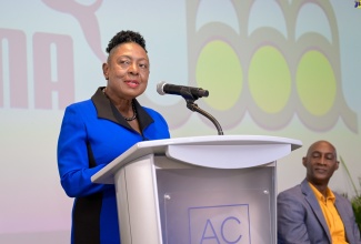 Minister of Culture, Gender, Entertainment and Sport, Hon. Olivia Grange, speaks at the press briefing and launch of the Jamaica Athletics Administrative Association’s (JAAA) Jamaica Athletics Invitational held recently at the AC Hotel by Marriott Kingston. Seated is JAAA President, Garth Gayle.