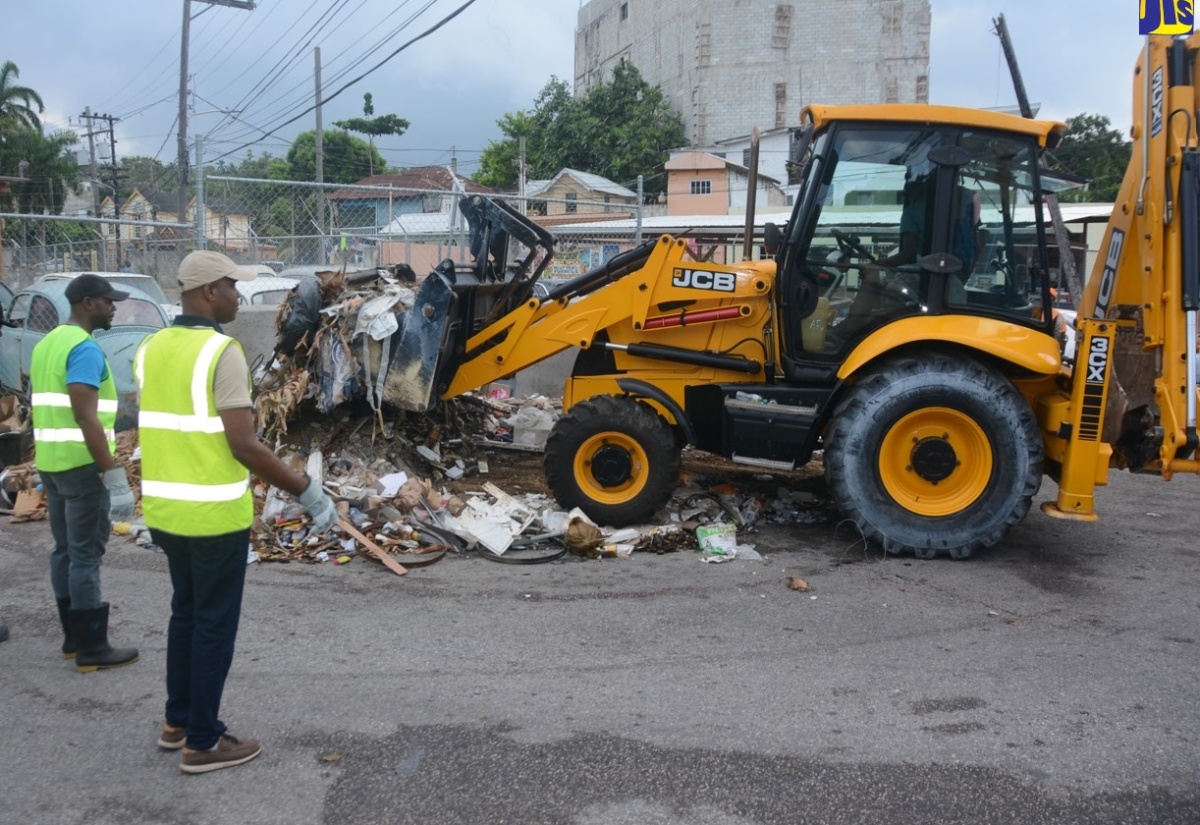 Mayor of Montego Bay and Chairman of the St. James Municipal Corporation, Councillor Richard Vernon (left) and Regional Operations Manager at WPM Waste Management Limited, Edward Muir, look on as garbage is removed from an illegal dump site at the Dome Street and Water Lane intersection in Montego Bay, St. James on Sunday (April 14), under the ‘MoBay STEP Up’ programme.