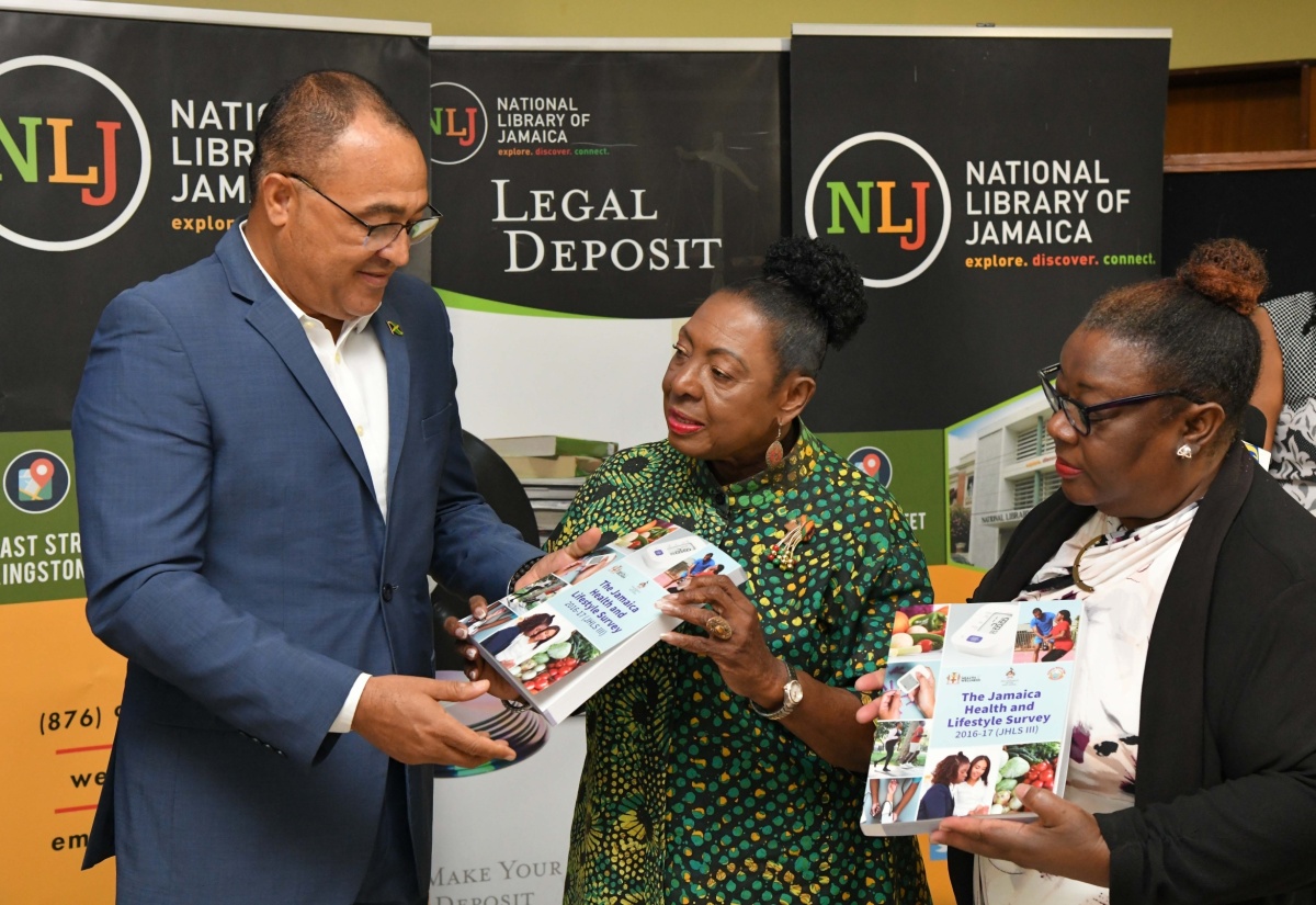 Minister of Health and Wellness, Dr. the Hon. Christopher Tufton (left), presents a copy of the Jamaica Health and Lifestyle Survey III, to Minister of Culture, Gender, Entertainment and Sport, Hon. Olivia Grange (centre), during the handover of the publication to the National Library of Jamaica (NLJ) on Tuesday (April 9), at the institution’s East Street offices in downtown Kingston. National Librarian, Beverley Lashley, holds a copy of the publication.