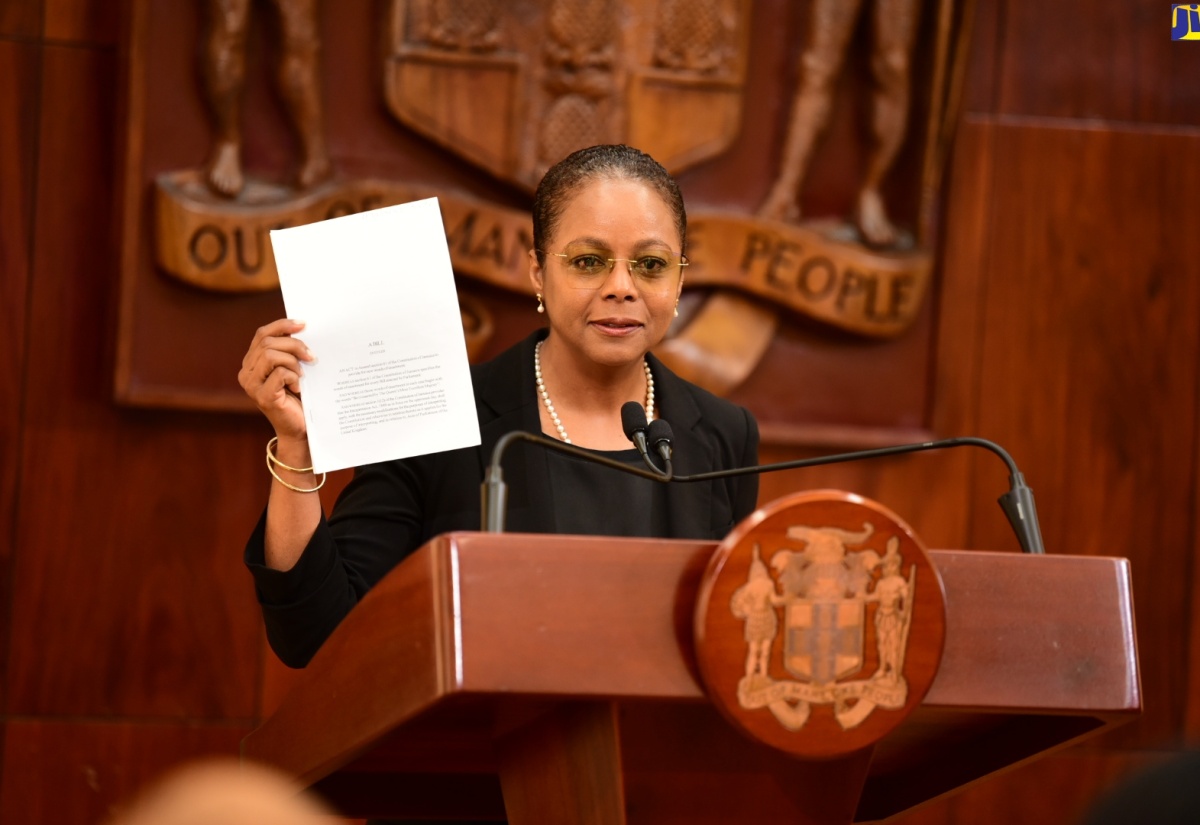 Minister of Legal and Constitutional Affairs, Hon. Marlene Malahoo Forte, displays a copy of the Bill to amend Section 61 of the Constitution of Jamaica to formulate new Words of Enactment, while speaking during a recent post-Cabinet press briefing at Jamaica House.

