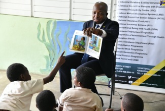 To commemorate 'Read Across Jamaica Day', Minister of Labour and Social Security, Hon. Pearnel Charles Jr., engages in an interactive reading session with children at the Early Stimulation Programme, during Read Across Jamaica Day activities at the institution in Kingston on Tuesday (May 7).

