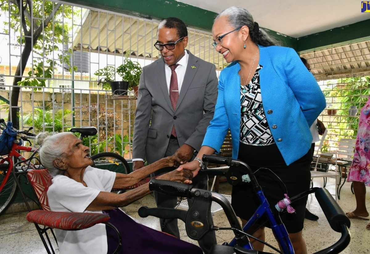 State Minister in the Ministry of Labour and Social Security, Dr. the Hon Norman Dunn and Permanent Secretary in the Ministry, Colette Roberts Risden (right), greet 101-year-old Adlin Sang (left), during a visit to her home on Rudolph Burke Avenue, Kingston 20, on Monday (May 20), as part of activities in observance of Centenarians’ Day.

