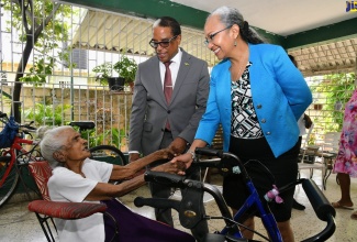 State Minister in the Ministry of Labour and Social Security, Dr. the Hon Norman Dunn and Permanent Secretary in the Ministry, Colette Roberts Risden (right), greet 101-year-old Adlin Sang (left), during a visit to her home on Rudolph Burke Avenue, Kingston 20, on Monday (May 20), as part of activities in observance of Centenarians’ Day.

