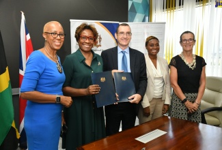 Permanent Secretary, Ministry of National Security, Ambassador Alison Stone Roofe (second left) and United Kingdom (UK) Development Representative for Jamaica, Oliver Blake (centre), display the signed Memorandum of Understanding (MOU) for the six-year Violence Prevention Partnership between the Government of Jamaica and the UK, at the offices of the Ministry of National Security in Kingston. They are flanked by (from left), Minister of Education and Youth, Hon. Fayval Williams; State Minister, Ministry of National Security, Hon. Juliet Cuthbert-Flynn; and British High Commissioner to Jamaica, Her Excellency Judith Slater.

