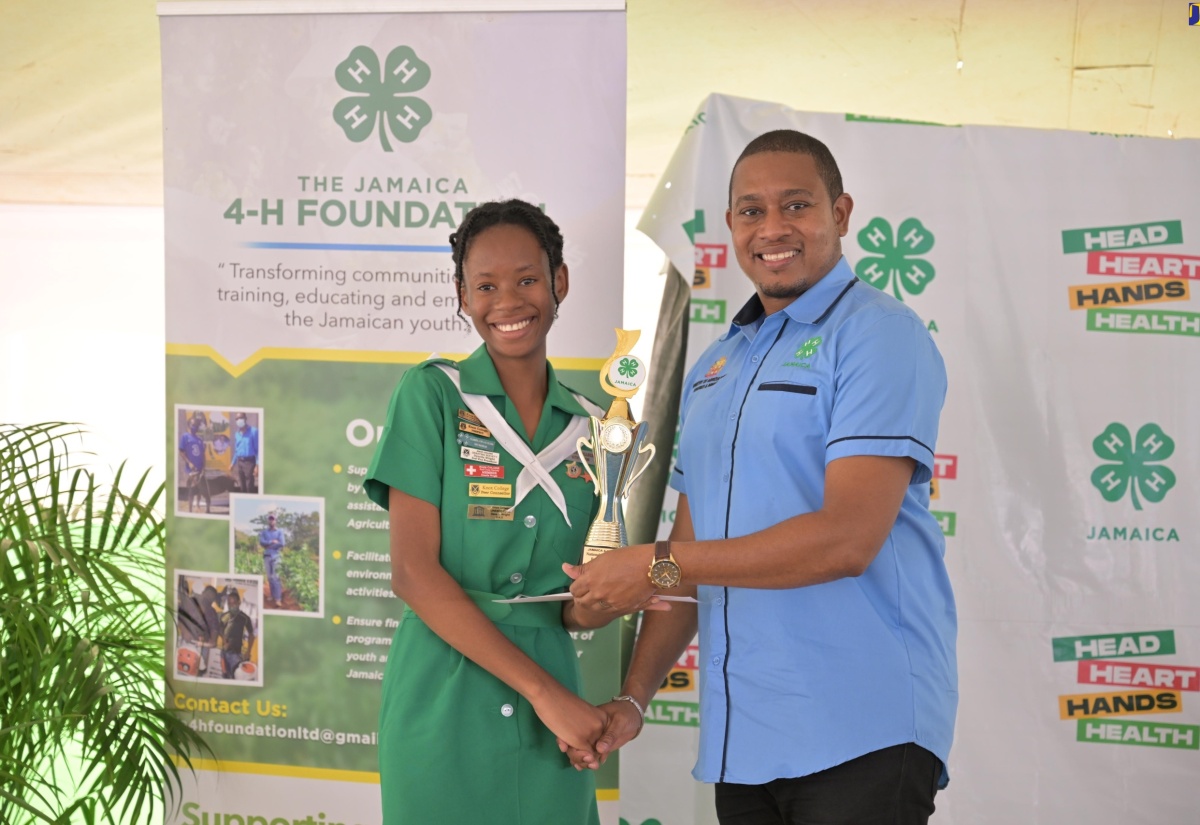 Minister of Agriculture, Fisheries and Mining, Hon. Floyd Green, hands over a trophy to the newly crowned Jamaica 4-H Clubs 2024 Female Youth Ambassador of the Year, Deneila Wright,  at the National Achievement Day, on May 10. Ms. Wright is a student at Knox College in Clarendon.

