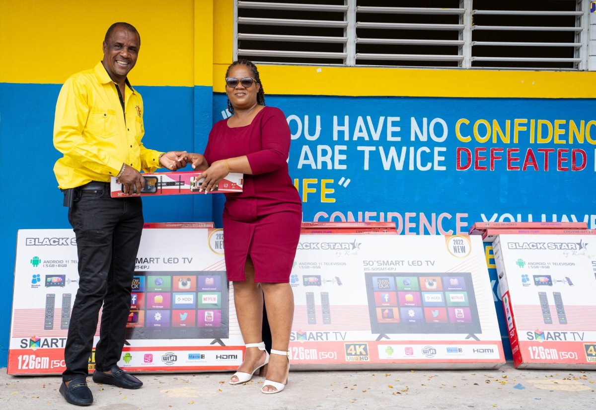 Principal of the Brown’s Hall Primary School, Novalin Leachman (right), accepts one of six, smart television sets from businessman and past student of the school,  Peter Perry, at the recent handover of the items at the institution in St. Catherine.