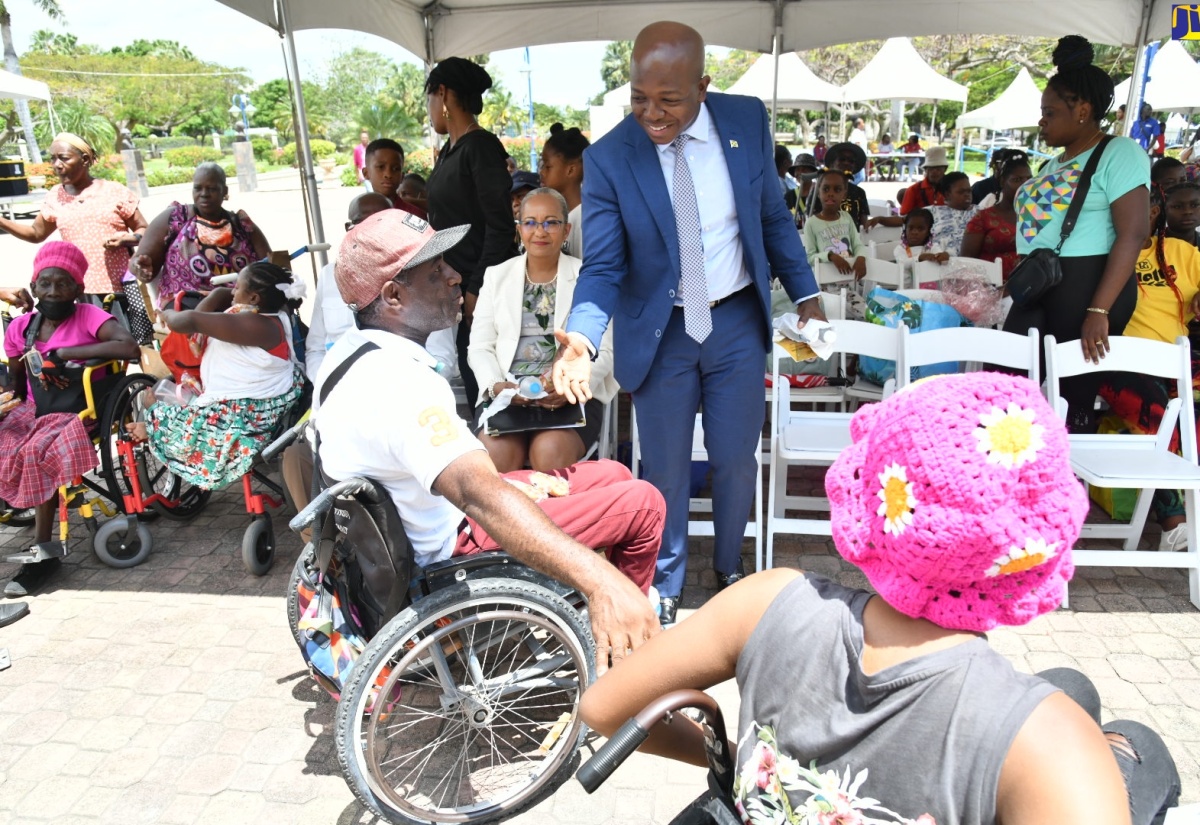 Minister of Labour and Social Security, Hon. Pearnel Charles Jr. (right), engages with members of the disabled community during the National Workers’ Week Expo on Wednesday (May 22) at Emancipation Park in St. Andrew.