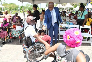 Minister of Labour and Social Security, Hon. Pearnel Charles Jr. (right), engages with members of the disabled community during the National Workers’ Week Expo on Wednesday (May 22) at Emancipation Park in St. Andrew.